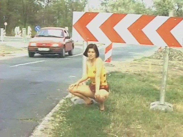 Redhead in pantyhose pisses under a street sign while the car is behind