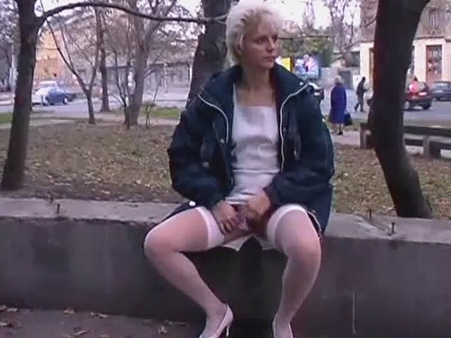 Mature blonde babe is touching herself in public and pisses on concrete